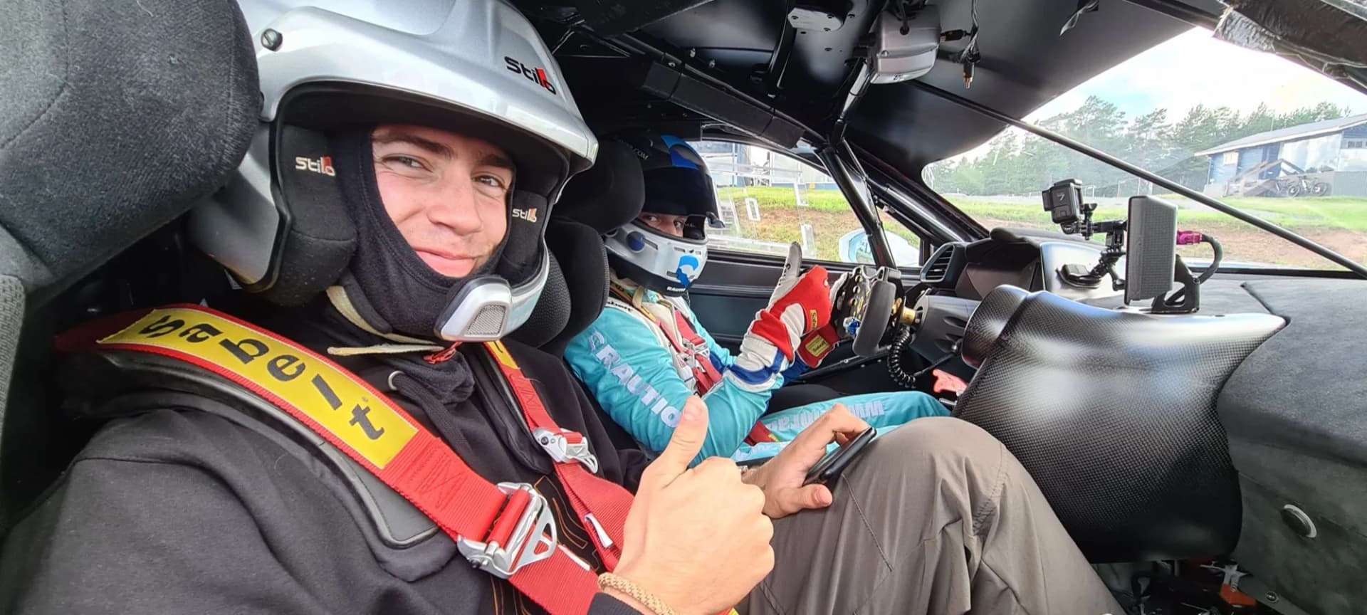 A passenger riding shotgun in a red race car on a closed track